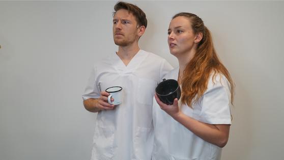 Zwei Pflegekräfte mit Kaffeetassen, die verärgert aussehen